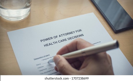 power of attorney for health care decisions. Writing a power of attorney form. Hand holding a pen and writing a form.