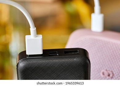 Power bank charges portable audio speaker using a USB cable. Close-up, selective focus