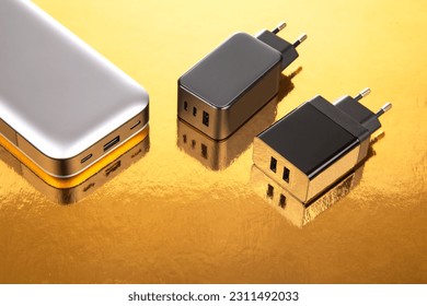 Power bank and charging plug on a golden background. Electronic devices for charging gadgets - Shutterstock ID 2311492033