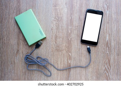 Power Bank, Smart Phone And USB Cable On Wooden Background