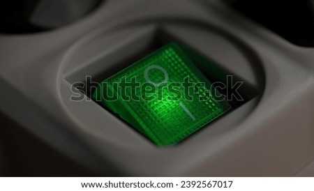 Power button of surge protector with green light. Close-up, shallow dof.