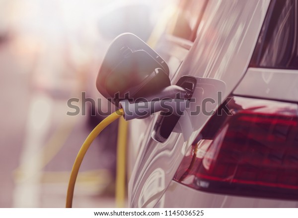 Power cable charging electric car with\
electricity.Charge batteries on station for new trip.Clean eco\
vehicle with new electrical engine.Care about environment riding\
hybrid cars.Innovative\
transport