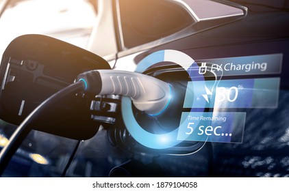 Power cable pump plug in charging power to electric vehicle EV car with modern technology UI control information display, car fueling station connected power cable alternative sustainable eco energy - Shutterstock ID 1879104058