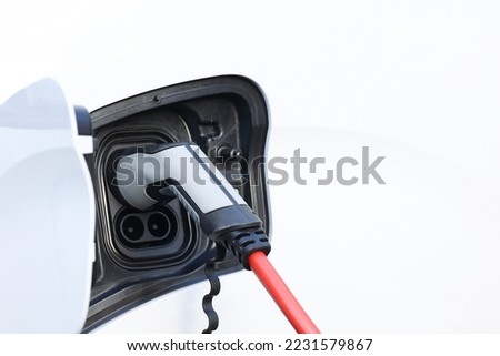 Power cable pump plug in charging power to electric vehicle EV car with modern technology UI control information display, car fueling station connected power cable alternative sustainable eco energy