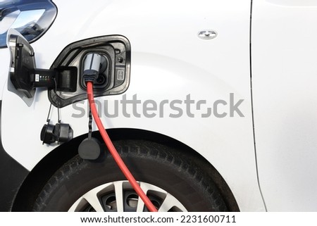 Power cable pump plug in charging power to electric vehicle EV truck with modern technology UI control information display, car fueling station connected power cable alternative sustainable eco energy