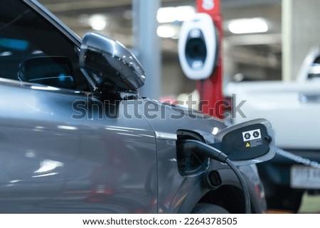 Power cable pump plug in charging power to electric vehicle EV car with modern technology UI control information display, car fueling station connected power cable alternative sustainable eco energy.