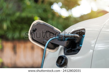 Power cable pump plug in charging power to electric vehicle EV car with green background.Technological advancement rechargeable EV car use alternative clean and sustainable energy. reduce CO2 emission