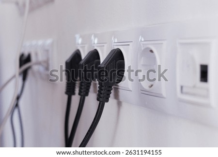 Power cables connected to electrical sockets on a wall