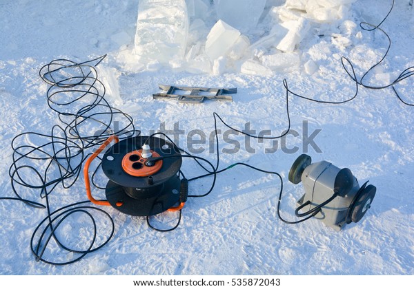 The power\
cord and the ice machine lie on the\
snow