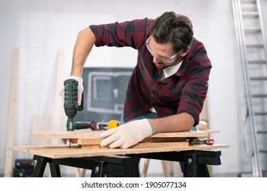 Power Electric Screwdriver. Carpenter Working With A Hand Tool On The Work Bench. Closeup View