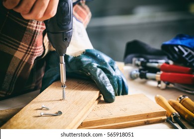 Power Electric Screwdriver. Carpenter Working With A Hand Tool On The Work Bench. Closeup View