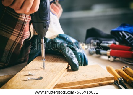 Power electric screwdriver. Carpenter working with a hand tool on the work bench. Closeup view