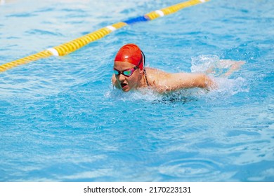 Power and energy. One female swimmer in swimming cap and goggles training at pool, outdoors. Healthy lifestyle, power, energy, sports movement concept. Woman swimming in summer time