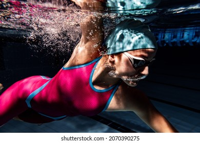 Power and enrgy. One female swimmer in swimming cap and goggles training at pool. Underwater view of swimming movements details. Healthy lifestyle, power, energy, sports movement concept. - Powered by Shutterstock