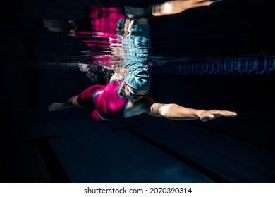 Power and enrgy. One female swimmer in swimming cap and goggles training at pool. Underwater view of swimming movements details. Healthy lifestyle, power, energy, sports movement concept.