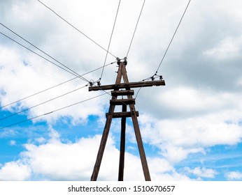 Power Line Support. Rustic Wooden Telegraph Pole Against A Blue Sky With Clouds At The Day Light. Electric Pole With Wires In The Russian, Soviet Village.