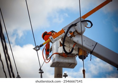 Power lineman maintaining electrical lines from an elevated work platform, ensuring safe and reliable electrical service. range high-visibility vest and hat, working clear blue sky to repair cables. - Powered by Shutterstock