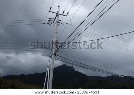 power lines crisscrossing in front of mountain on an ominous cloudy day