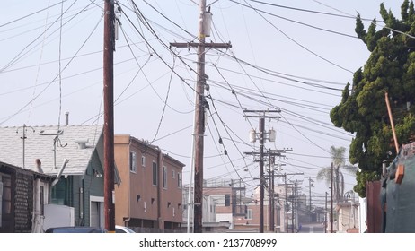 Power lines or wires on poles, foggy city street, California, USA. Cables on high voltage wooden electricity posts or pylons in misty San Diego. Power supply and houses in America. Cloudy weather.