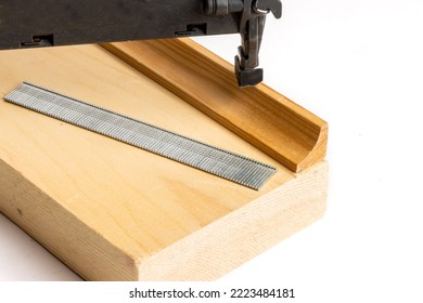 A Power Nail Gun With A Strip Of Finishing Nails Attaching A Piece Of Wood Trim Molding Isolated On White