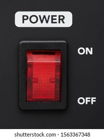 Power on and off electrical switch red button on black background. Close up detail. 