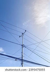 Power pole and electricity cables against blue sky - Shutterstock ID 2395475055