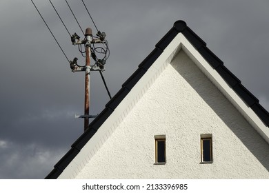 Power pole with grounding on white gable, dramatic stormy sky, concept: energy, electricity, power, supply, dependence, threat (horizontal), Dahlbruch, NRW, Germany