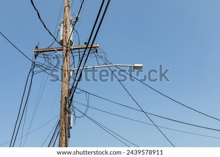 Power pole with lines and cables, street lamp and transformer attached against a blue sky, creative copy space, horizontal aspect