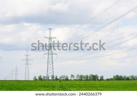 The power poles are located among a green field, against a blue sky with white clouds. High quality photo