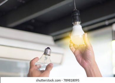 Power Saving Concept. Asia Man Changing Compact-fluorescent (CFL) Bulbs With New LED Light Bulb.
