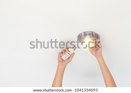 Power saving electrical efficiency concept. Hands changing compact-fluorescent (CFL) bulbs with new LED light bulb copyspace.