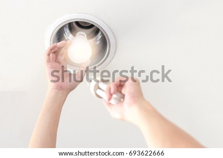 Power saving electrical efficiency concept. Hands changing compact-fluorescent (CFL) bulbs with new LED light bulb.