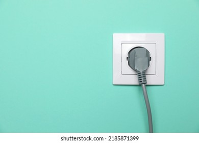 Power socket with inserted plug on turquoise wall, space for text. Electrical supply - Shutterstock ID 2185871399