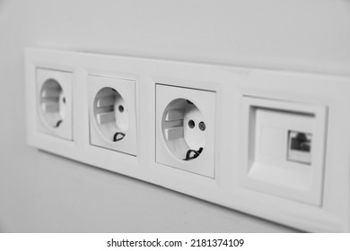 Power sockets on white wall, closeup. Electrical supply