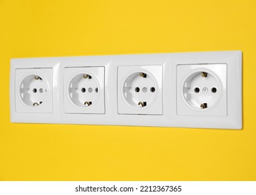Power sockets on yellow wall, closeup. Electrical supply