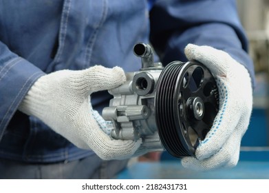 A power steering pump is in the hands of an auto mechanic. Close-up. Compliance and integrity control of the new spare part. Repair and maintenance of a car in a car service center.