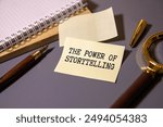 THE POWER OF STORYTELLING inscription in a white notebook on the table next to a calculator, pen, numbers on a sheet of paper. Tax concept