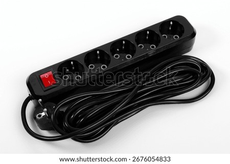 A power strip features five sockets for connecting various electrical devices. It includes a long black cable and a red on-off switch for easy operation. Ideal for home or office use.