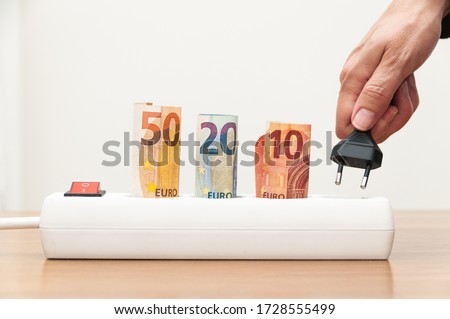 power strip with rolled 50,20 and 10 euro bills and woman's hand putting plug on white background. concept of the high cost of electricity in the pandemic or coronavirus or covid-19 due to home confin