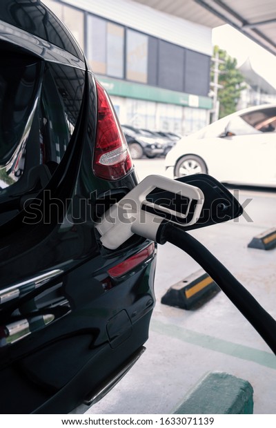 power\
supply connects to plug-in electric vehicle or electric car at\
charging station in car park area of shopping plaza. charging\
technology for future automotive and city\
life.