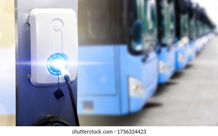 Power supply for electric car charging. Electric car charging station. Close up of the power supply plugged into an electric car being charged. Blue tourist buses on parking 