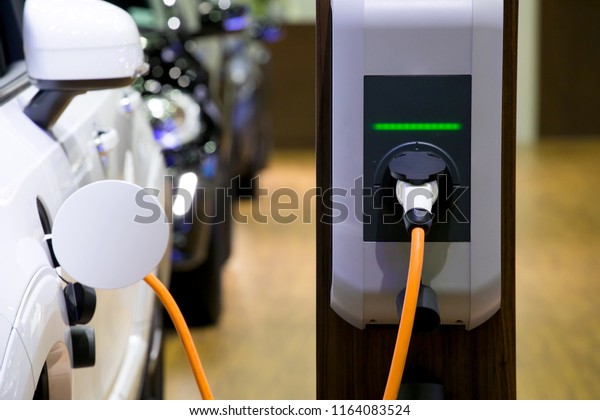Power supply for electric car charging. Electric\
car charging station. Close up of the power supply plugged into an\
electric car being\
charged.