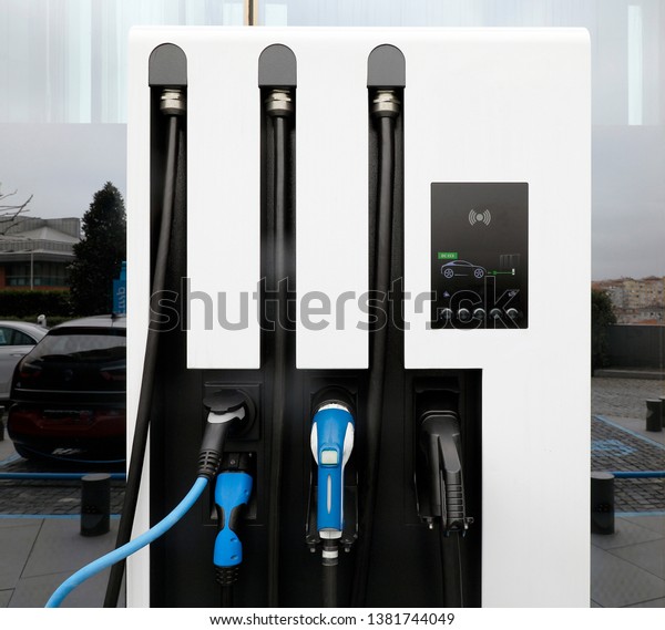 Power supply for electric car charging.\
Electric car charging station. Close up of the power supply plugged\
into an electric car being charged.\
