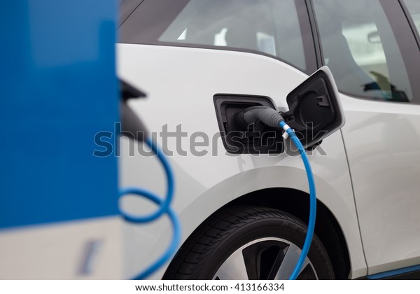 Power supply for electric car charging. \
Electric car charging station. Close up of the power supply plugged\
into an electric car being\
charged.