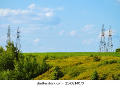 Power Transmission Towers. Air hi-voltage electric line supports at field under blue sky. Belgorod region landscape.