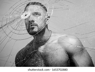 Power and vitality. Latino man full of power and energy looking through broken glass. Strong hispanic guy training power and endurance. Developing of muscular power and strength.