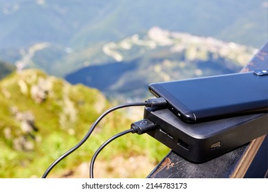 Powerbank charges the phone on the background of the mountains