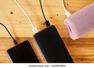 Powerbank charges smartphone and portable speaker using usb. Close-up, selective focus