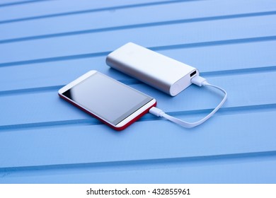 Powerbank Charging Smartphone - Outdoor, Blue Wooden Background