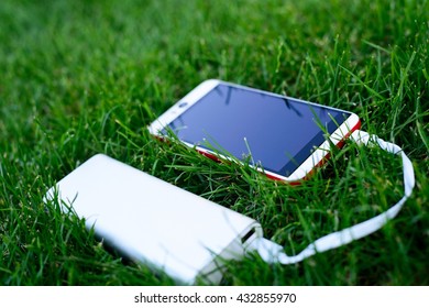 Powerbank Charging White And Red Smartphone - Outdoor, Grass